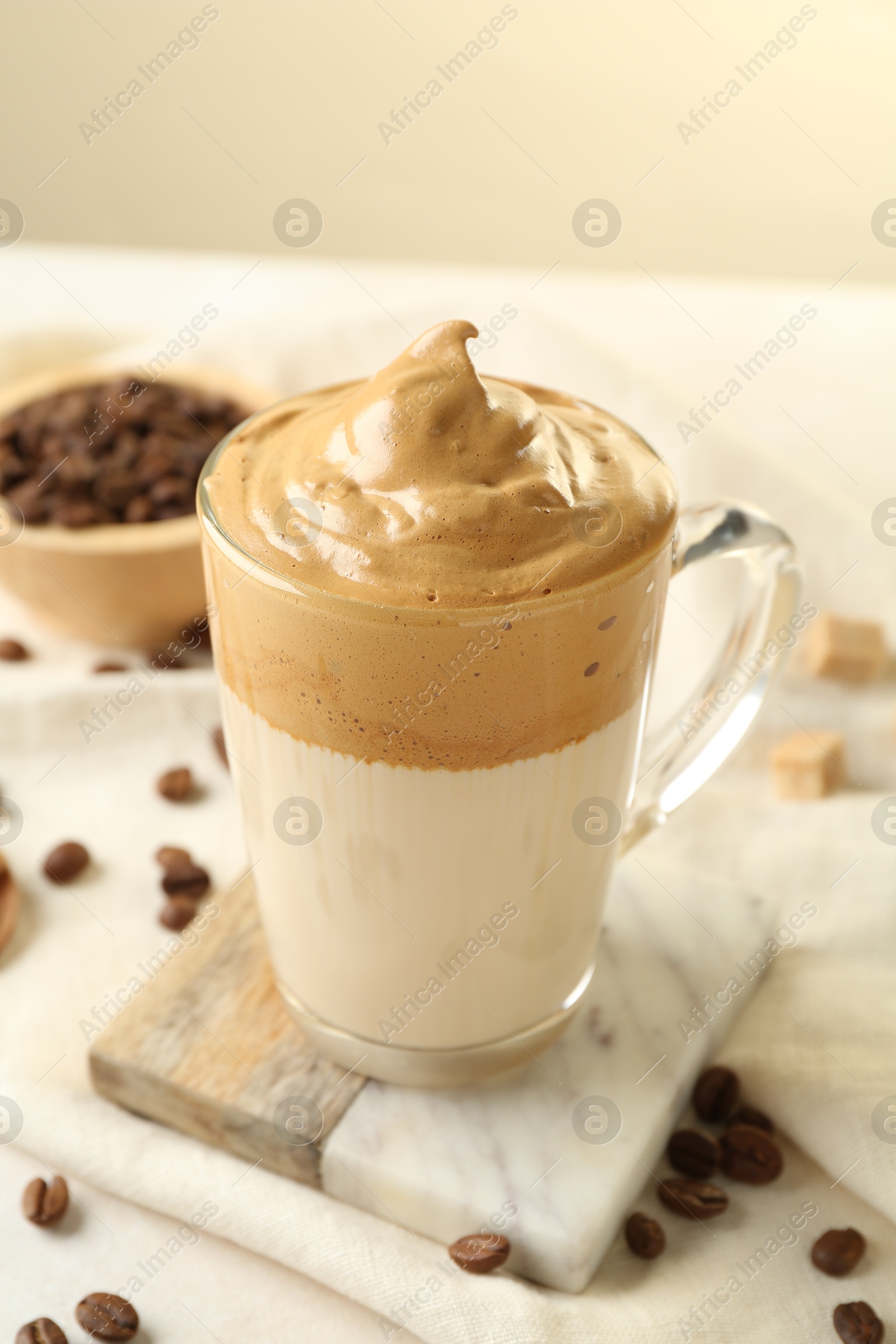 Delicious dalgona coffee in glass cup and beans on table, closeup Photo of Delicious dalgona coffee in glass cup and beans on table, closeup
