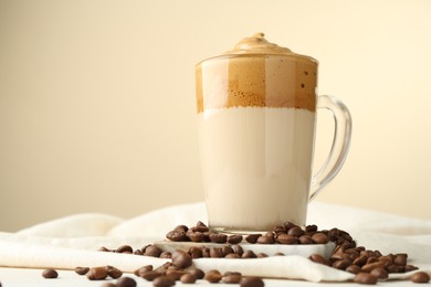 Photo of Delicious dalgona coffee in glass cup and beans on table, low angle view. Space for text