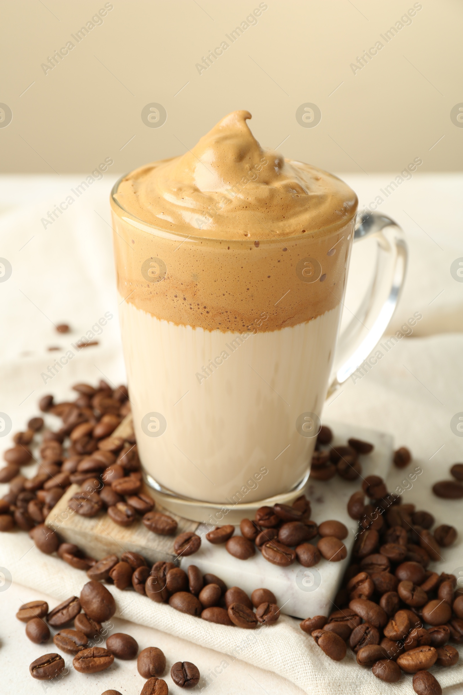 Delicious dalgona coffee in glass cup and beans on table, closeup Photo of Delicious dalgona coffee in glass cup and beans on table, closeup