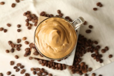 Photo of Delicious dalgona coffee in glass cup and beans on table, flat lay