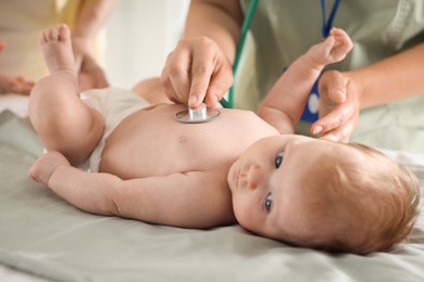 Photo of Mother and her cute little child having appointment with pediatrician in hospital. Doctor examining baby with stethoscope, closeup