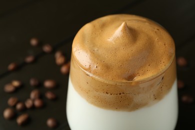 Photo of Delicious dalgona coffee in glass and beans on table, closeup. Space for text