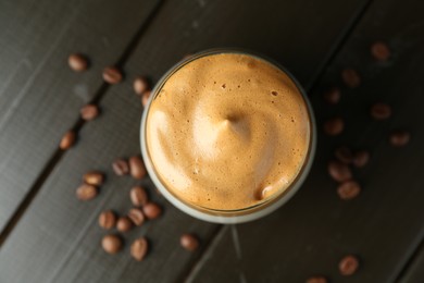 Photo of Delicious dalgona coffee in glass and beans on wooden table, flat lay