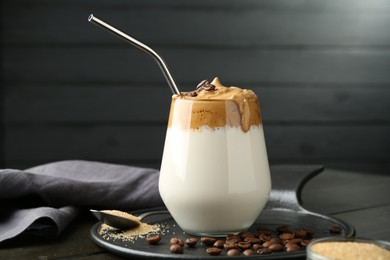 Photo of Delicious dalgona coffee in glass, beans and brown sugar on wooden table, closeup