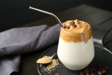 Photo of Delicious dalgona coffee in glass, beans and brown sugar on wooden table, closeup