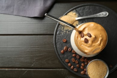 Photo of Delicious dalgona coffee in glass, beans and brown sugar on wooden table, top view. Space for text