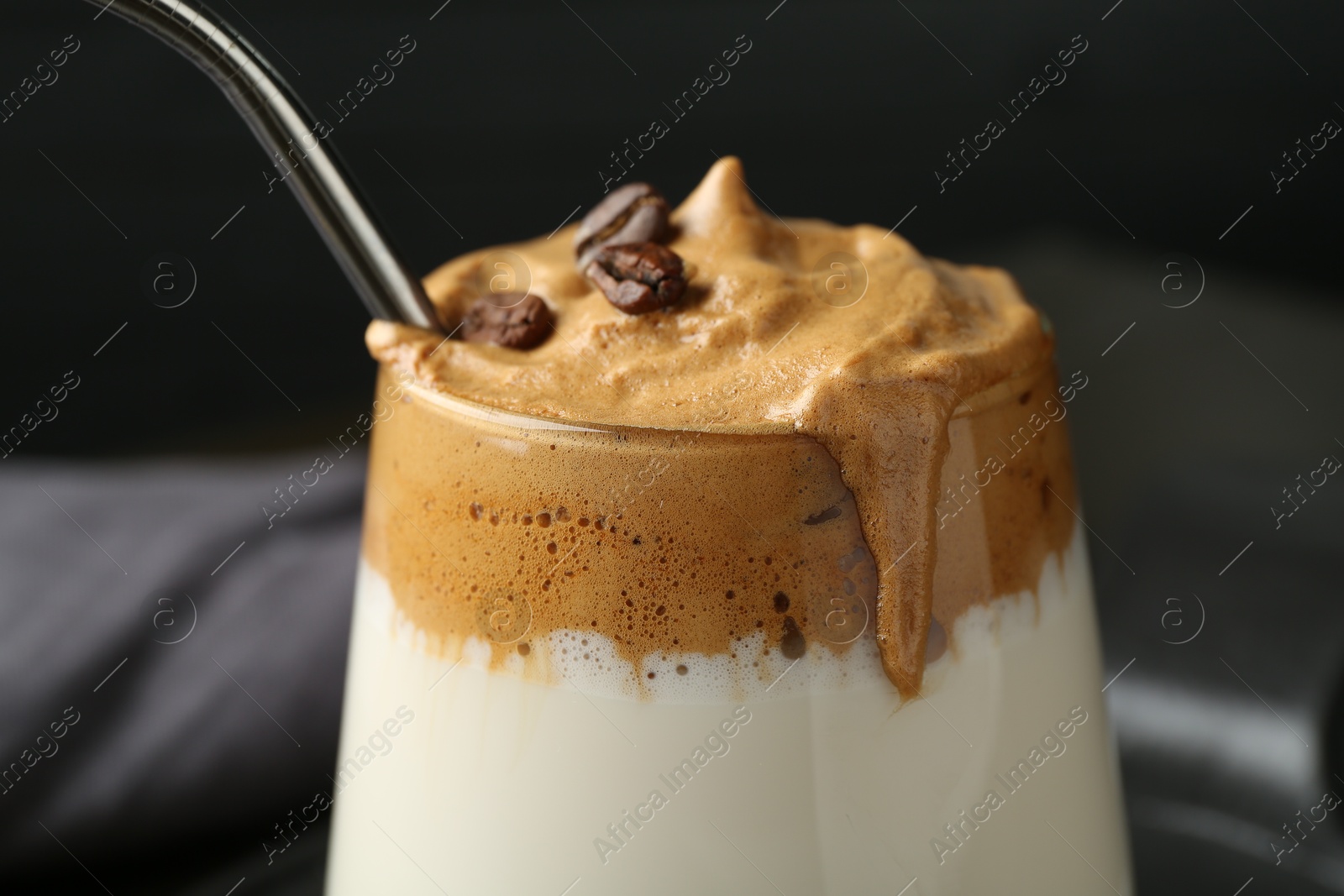 Photo of Delicious dalgona coffee in glass on blurred background, closeup