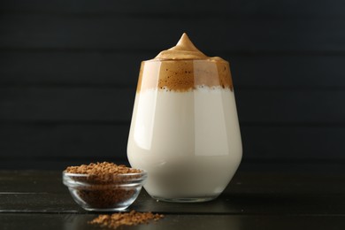 Photo of Delicious dalgona coffee in glass and granules on wooden table, closeup