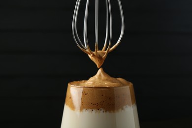 Photo of Pouring cream for dalgona coffee into glass on blurred background, closeup