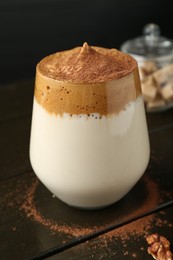 Photo of Delicious dalgona coffee in glass on wooden table, closeup