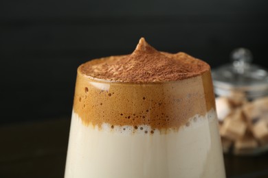 Photo of Delicious dalgona coffee in glass on blurred background, closeup