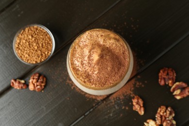Photo of Delicious dalgona coffee in glass, granules, walnuts and brown sugar on wooden table, flat lay