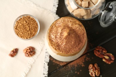 Photo of Delicious dalgona coffee in glass, granules, walnuts and brown sugar on wooden table, flat lay