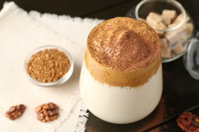 Photo of Delicious dalgona coffee in glass, granules, walnuts and brown sugar on wooden table, above view