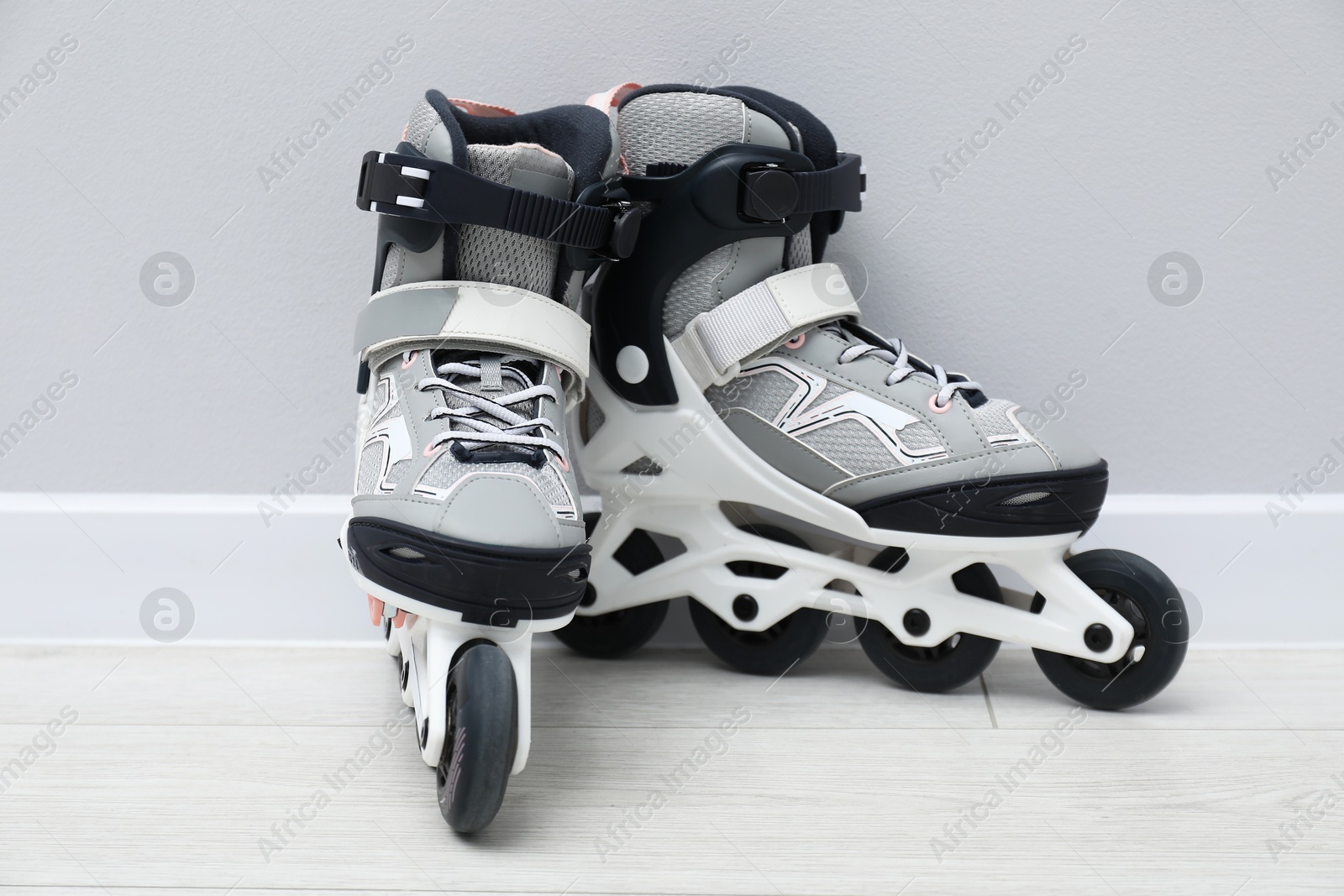 Photo of Pair of roller skates on floor near white wall