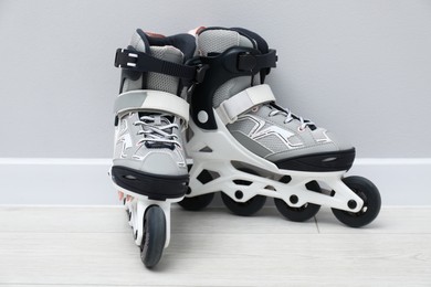 Photo of Pair of roller skates on floor near white wall