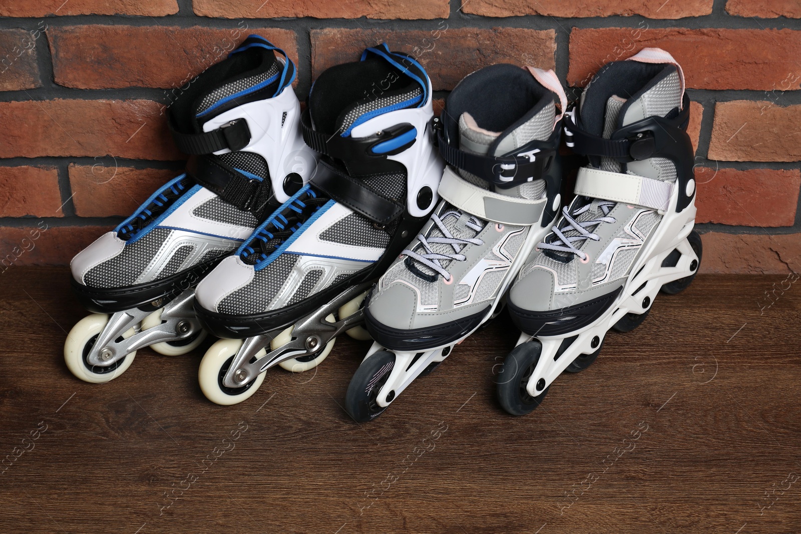 Pairs of roller skates on wooden table near brick wall Photo of Pairs of roller skates on wooden table near brick wall