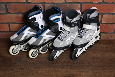 Photo of Pairs of roller skates on wooden table near brick wall