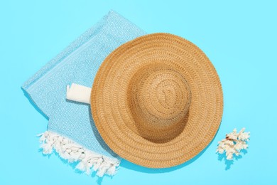 Photo of Straw hat, beach towel and coral on light blue background, flat lay
