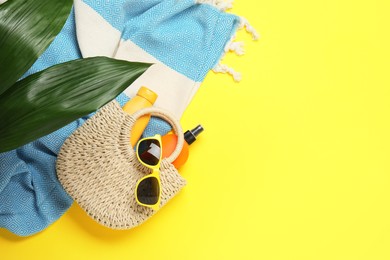 Photo of Flat lay composition with beach towel and other summer accessories on yellow background. Space for text
