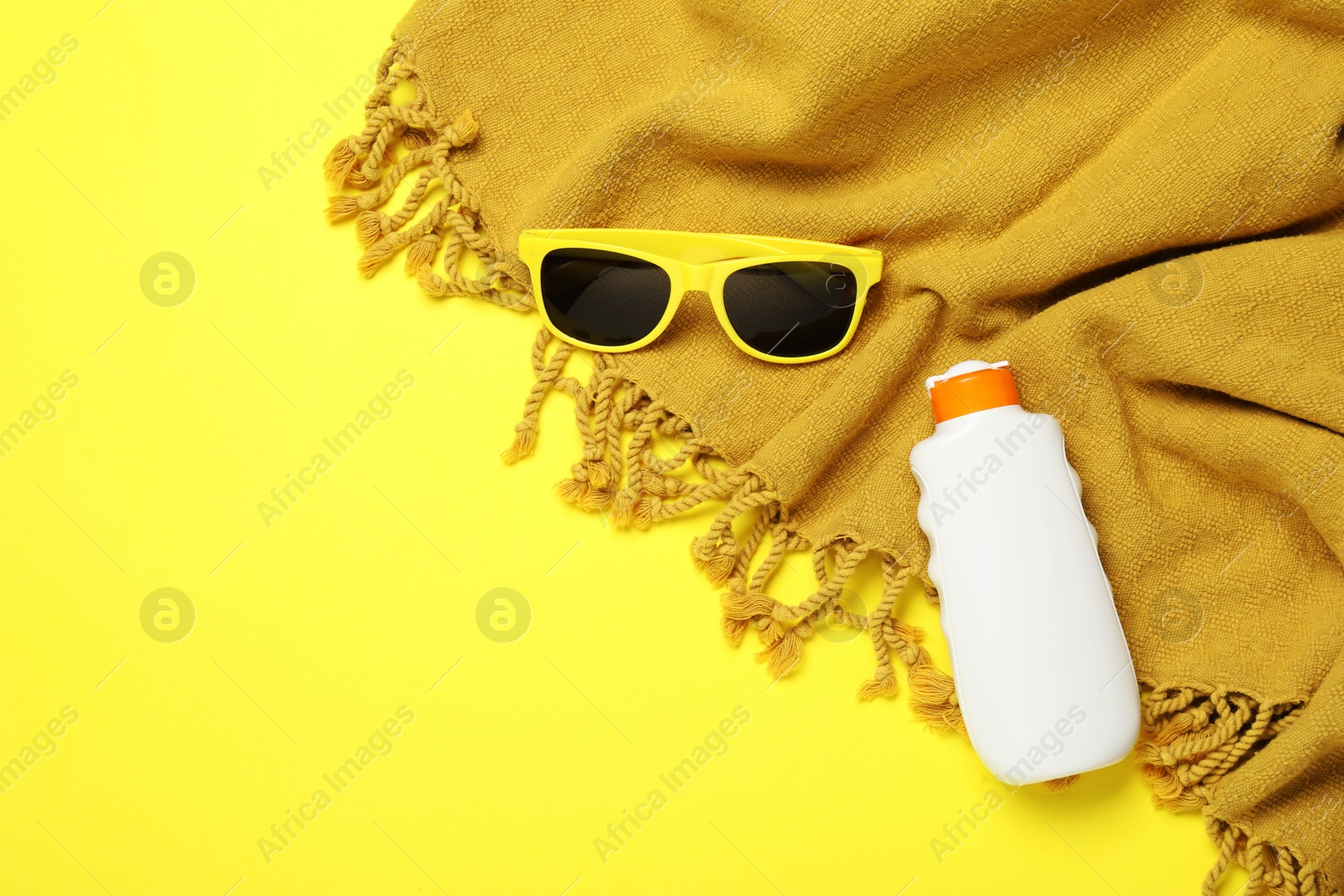 Beach towel, sunglasses and sunscreen on yellow background, flat lay. Space for text Photo of Beach towel, sunglasses and sunscreen on yellow background, flat lay. Space for text