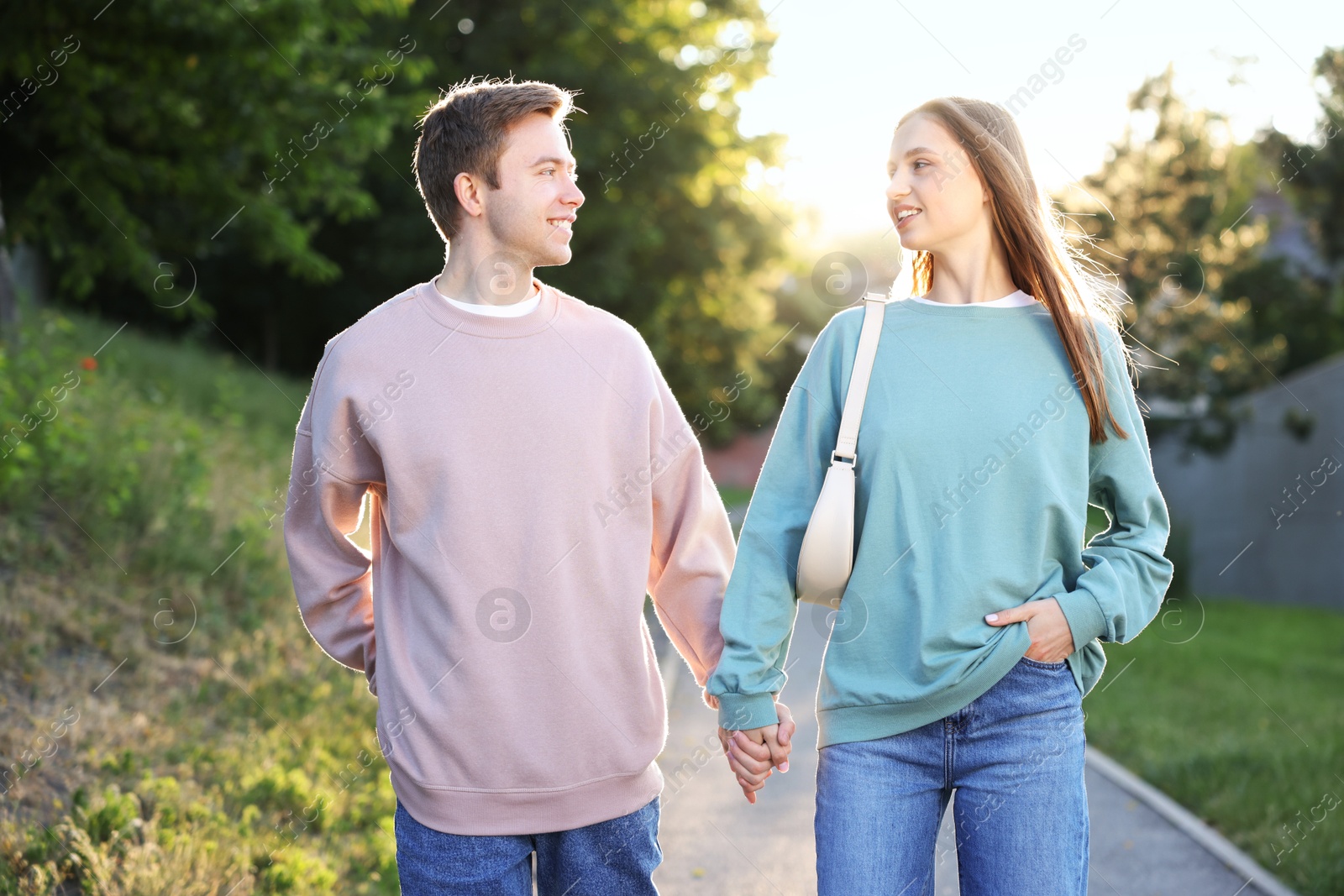 Lovely couple walking together in park on sunny day Photo of Lovely couple walking together in park on sunny day
