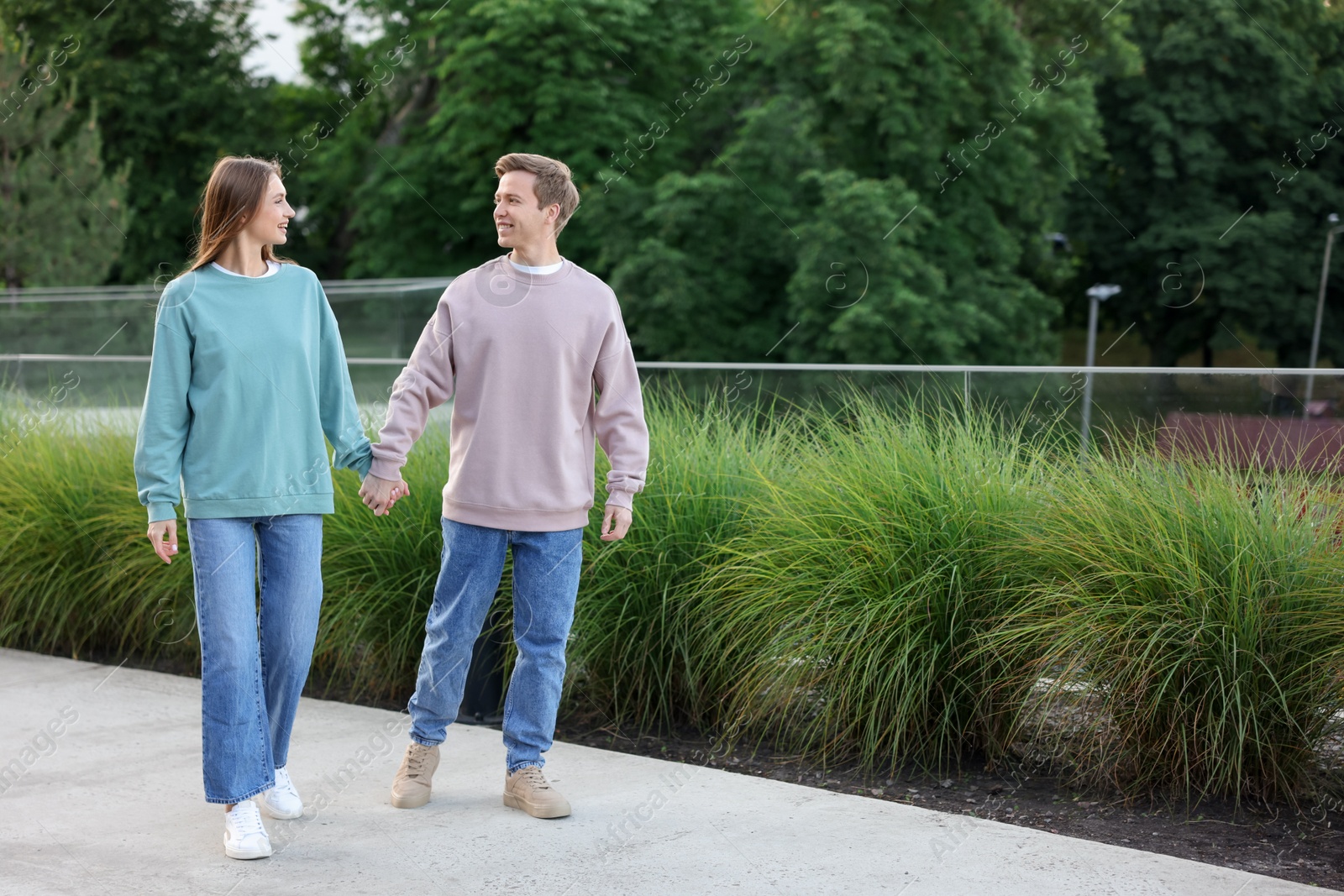 Lovely couple walking together on city street, space for text Photo of Lovely couple walking together on city street, space for text