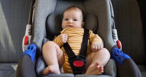 Photo of Cute little baby fastened in car seat
