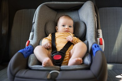 Photo of Cute little baby fastened in car seat