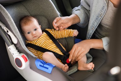Photo of Mother fastening her baby in car seat, closeup
