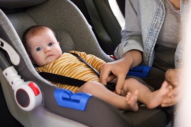 Photo of Mother fastening her baby in car seat, closeup