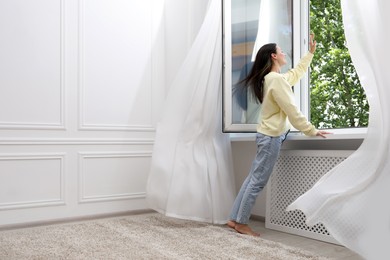 Photo of Harmony. Smiling woman near open window at home. Space for text