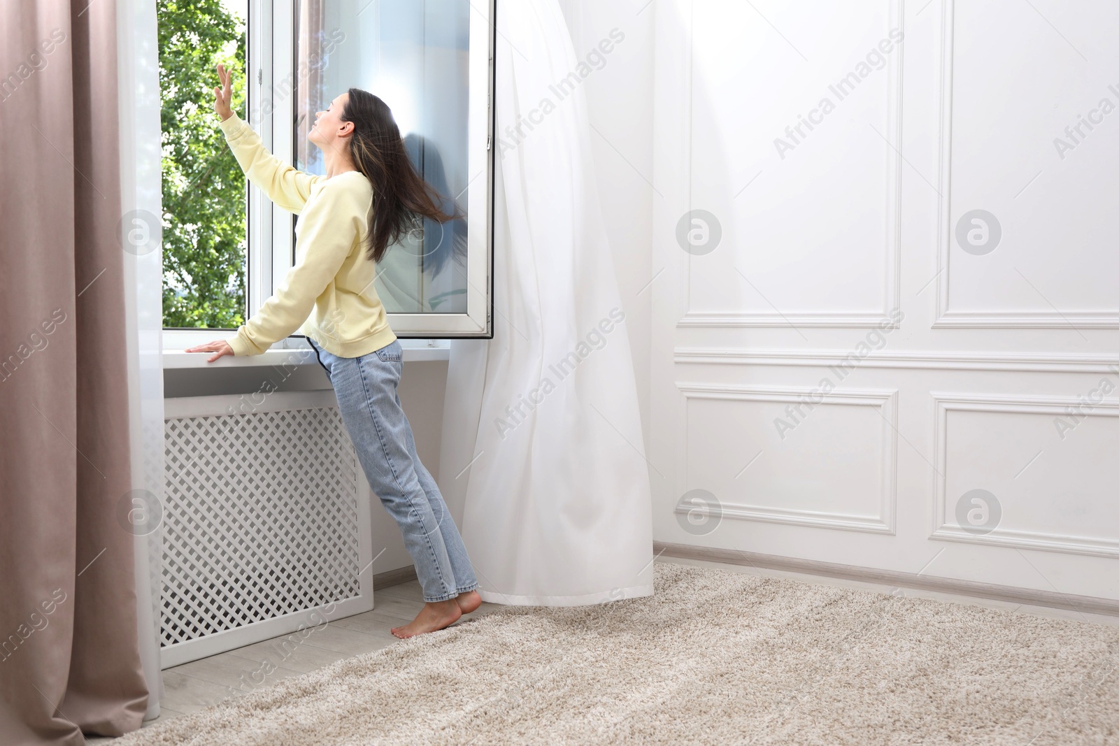 Harmony. Smiling woman near open window at home. Space for text Photo of Harmony. Smiling woman near open window at home. Space for text