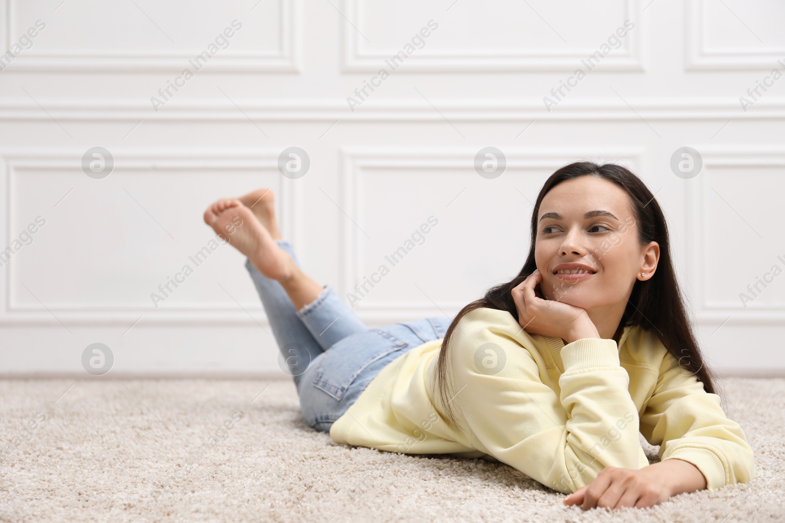 Photo of Harmony. Smiling woman lying on floor near white wall at home