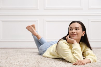 Photo of Harmony. Smiling woman lying on floor near white wall at home