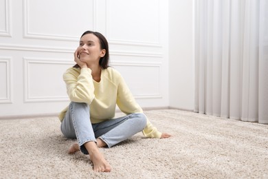 Photo of Harmony. Smiling woman sitting on floor near white wall at home