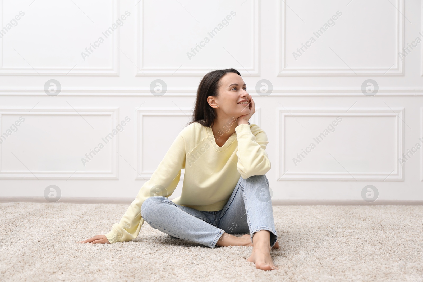 Harmony. Smiling woman sitting on floor near white wall at home Photo of Harmony. Smiling woman sitting on floor near white wall at home