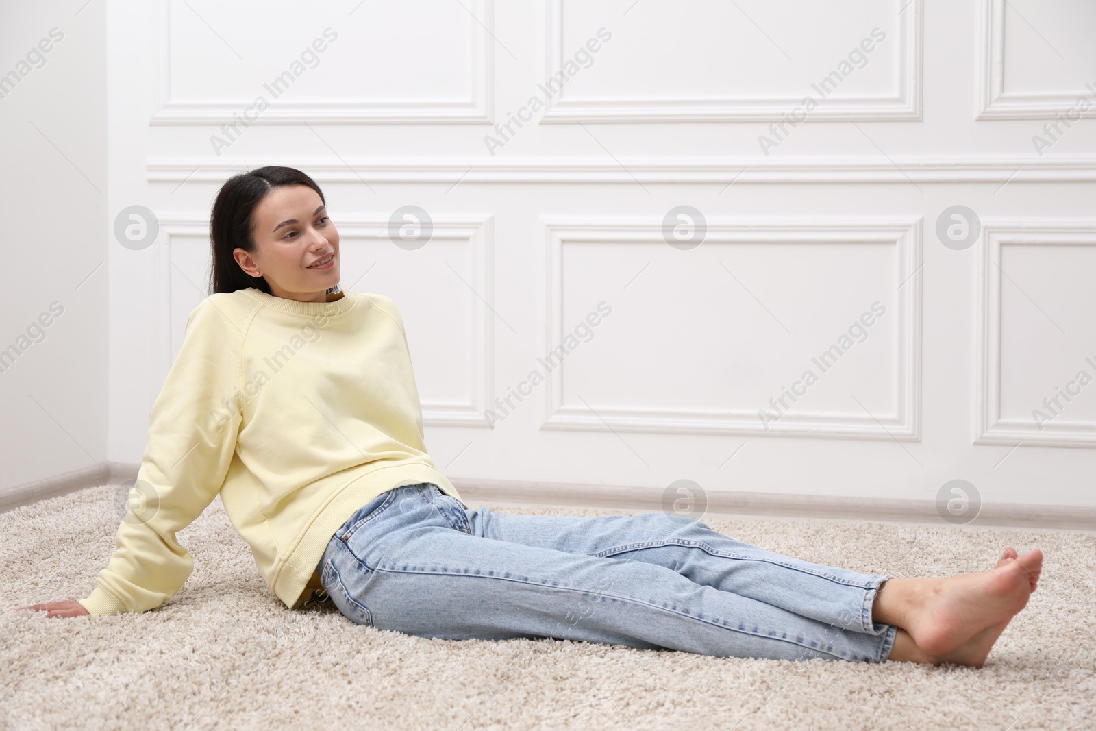Harmony. Smiling woman sitting on floor near white wall at home Photo of Harmony. Smiling woman sitting on floor near white wall at home