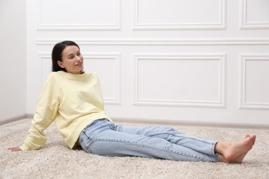 Photo of Harmony. Smiling woman sitting on floor near white wall at home