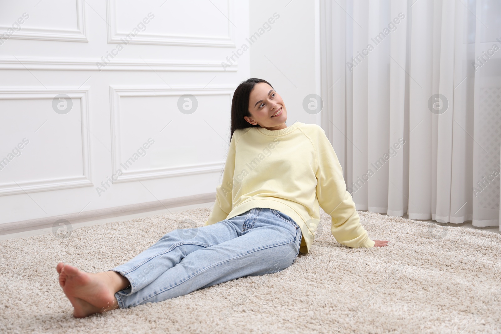 Harmony. Smiling woman sitting on floor near white wall at home Photo of Harmony. Smiling woman sitting on floor near white wall at home