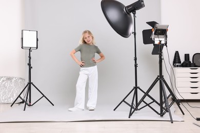 Photo of Little girl on light grey background in photo studio with professional equipment