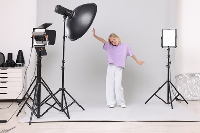 Photo of Little girl on light grey background in photo studio with professional equipment