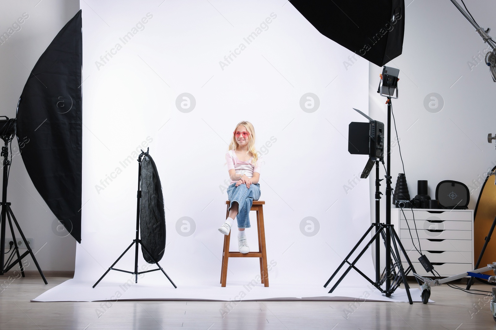 Little girl on white background in photo studio with professional equipment Photo of Little girl on white background in photo studio with professional equipment