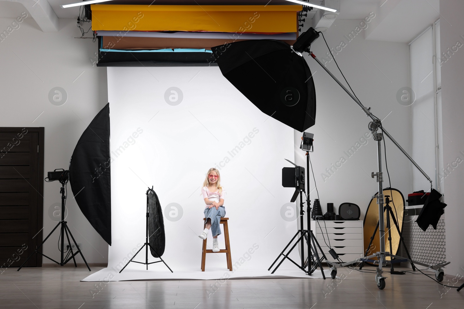 Little girl on white background in photo studio with professional equipment Photo of Little girl on white background in photo studio with professional equipment