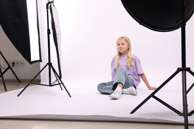 Photo of Little girl on white background in photo studio with professional equipment