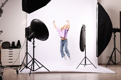 Photo of Little girl jumping on white background in photo studio with professional equipment