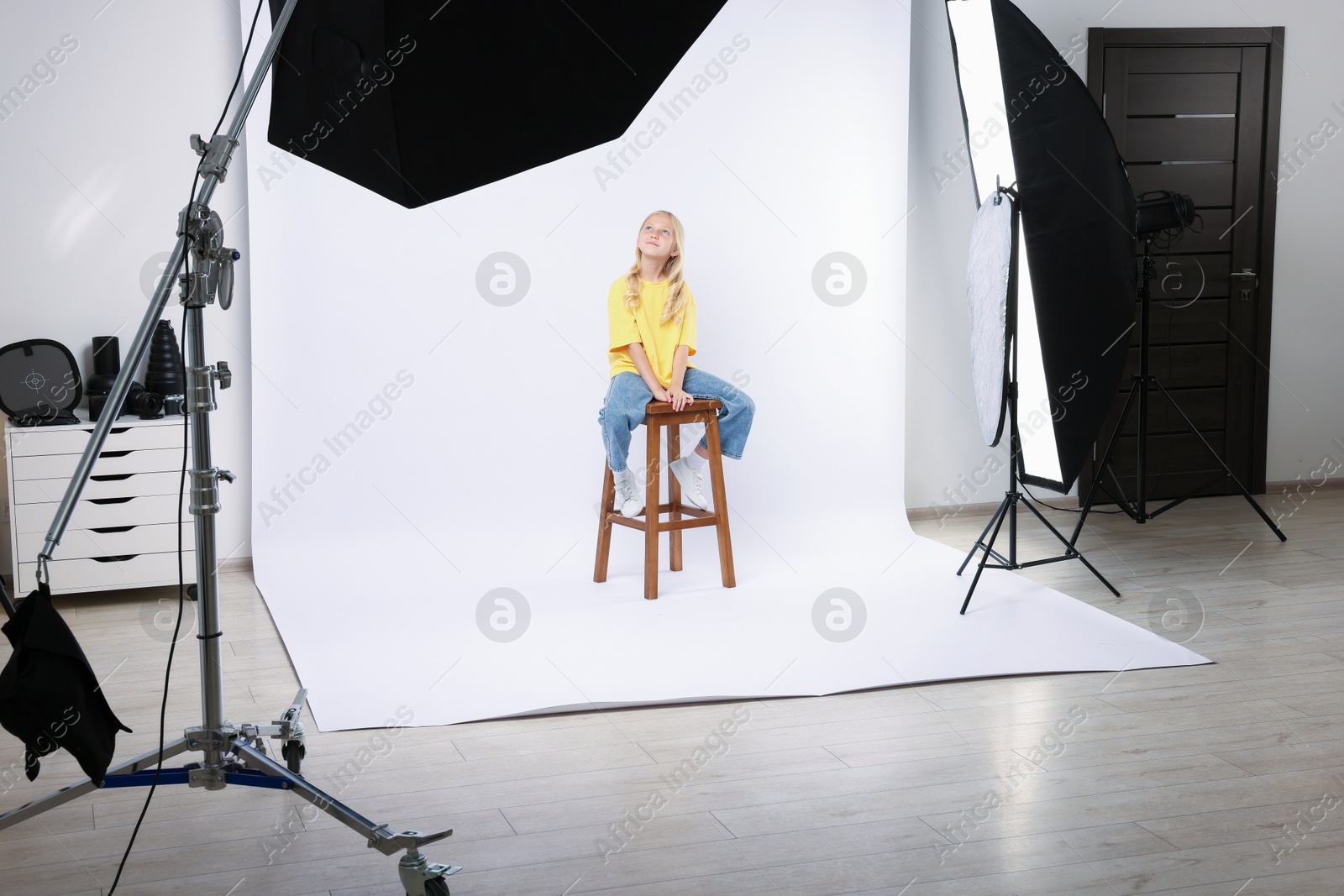 Little girl on white background in photo studio with professional equipment Photo of Little girl on white background in photo studio with professional equipment