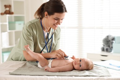 Photo of Mother and her cute little child having appointment with pediatrician in hospital. Doctor examining baby with stethoscope