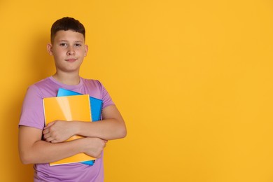 Photo of Teenage boy with notebooks on orange background, space for text