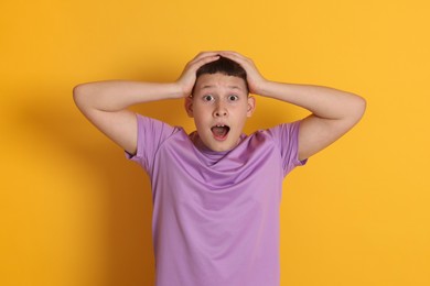Photo of Portrait of shocked teenage boy on orange background